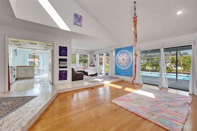 entrance foyer with light wood-style floors, vaulted ceiling, a textured ceiling, and recessed lighting