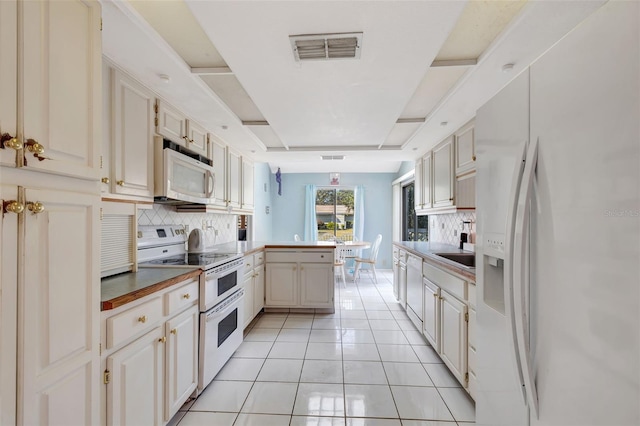 kitchen featuring white appliances, visible vents, a peninsula, backsplash, and light tile patterned flooring