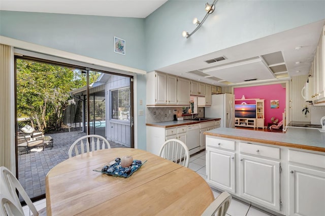 dining space with light tile patterned floors, high vaulted ceiling, and visible vents