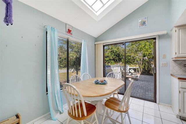 dining room with light tile patterned floors and vaulted ceiling with skylight