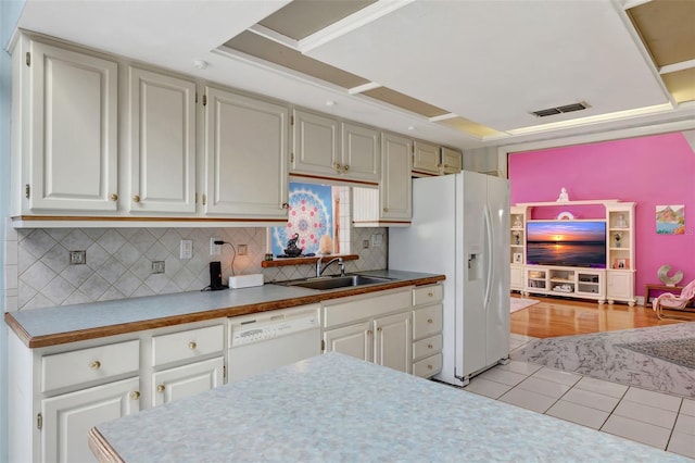 kitchen with light tile patterned flooring, white appliances, a sink, visible vents, and tasteful backsplash