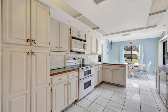 kitchen with white appliances, tasteful backsplash, light tile patterned floors, visible vents, and a peninsula