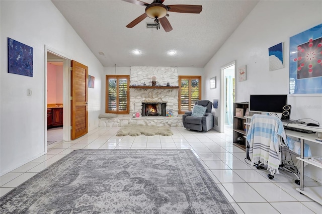 living area with a fireplace, light tile patterned floors, visible vents, ceiling fan, and vaulted ceiling