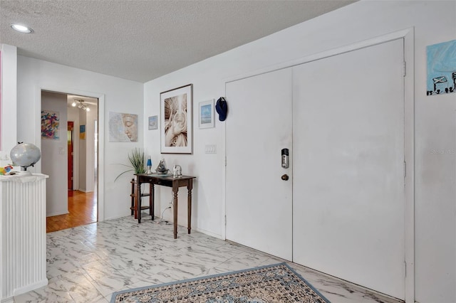 foyer entrance with marble finish floor and a textured ceiling