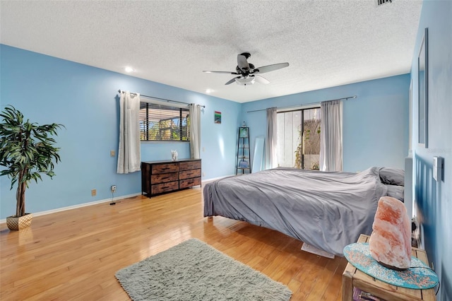 bedroom with visible vents, a ceiling fan, a textured ceiling, wood finished floors, and baseboards