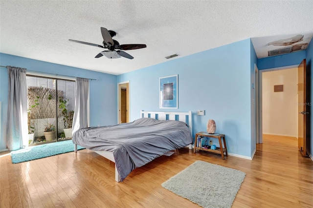 bedroom featuring a textured ceiling, a ceiling fan, baseboards, visible vents, and light wood-style floors