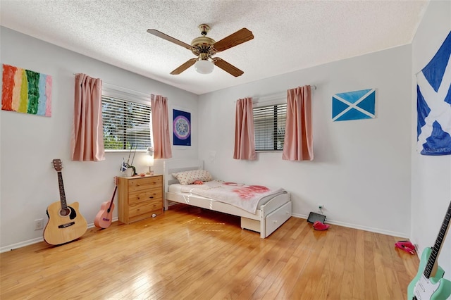 bedroom featuring a textured ceiling, hardwood / wood-style floors, a ceiling fan, and baseboards