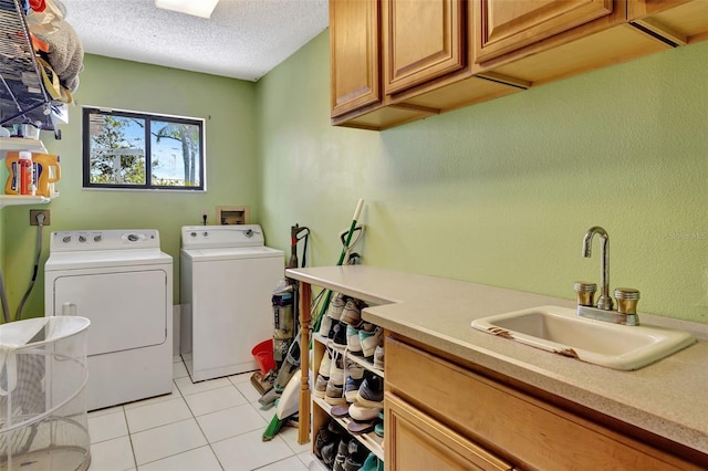 laundry room with washer and clothes dryer, light tile patterned floors, cabinet space, a sink, and a textured ceiling