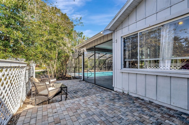 view of patio with glass enclosure, fence, and an outdoor pool