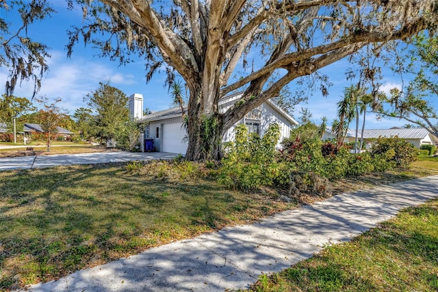 view of front of house with driveway, a chimney, and a front lawn