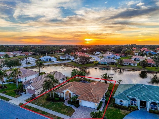 aerial view at dusk featuring a water view