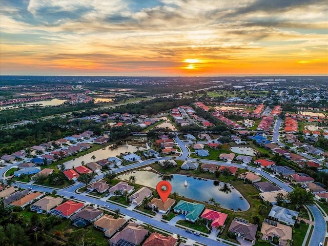 aerial view at dusk featuring a water view