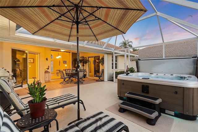 patio terrace at dusk with a lanai and a hot tub