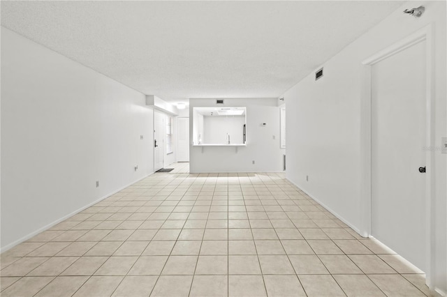 tiled empty room featuring a textured ceiling