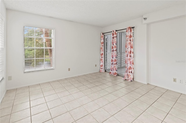 empty room featuring a textured ceiling and light tile patterned floors