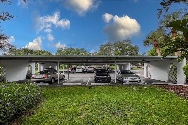 view of parking / parking lot with a carport and a lawn