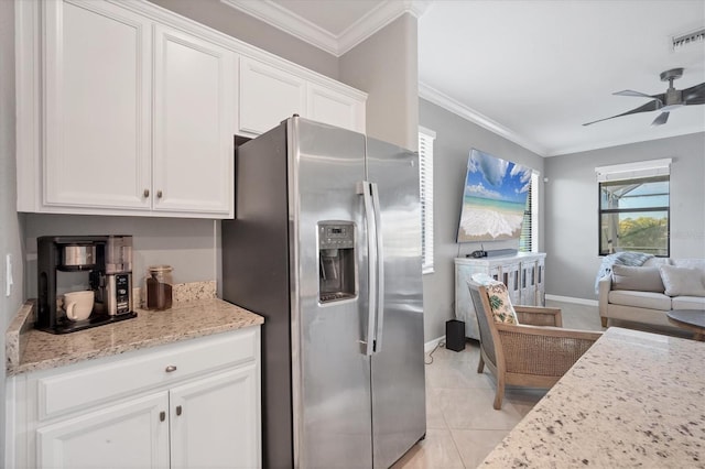 kitchen with white cabinets, stainless steel fridge, ornamental molding, light tile patterned floors, and light stone counters