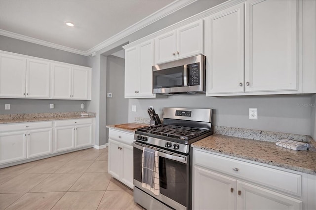 kitchen with light stone counters, light tile patterned floors, ornamental molding, stainless steel appliances, and white cabinets