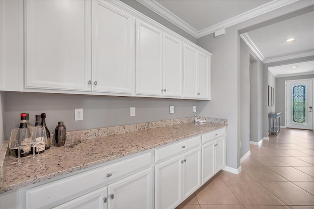 kitchen with light stone counters, light tile patterned floors, crown molding, and white cabinets