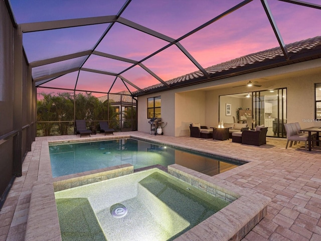 pool at dusk featuring a patio, an in ground hot tub, ceiling fan, glass enclosure, and an outdoor living space