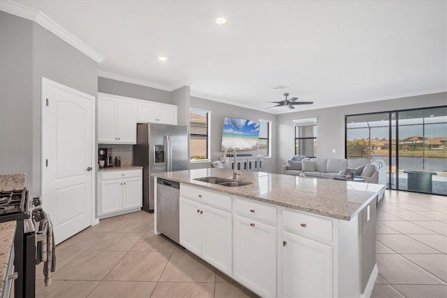 kitchen featuring appliances with stainless steel finishes, sink, white cabinets, light tile patterned floors, and a center island with sink