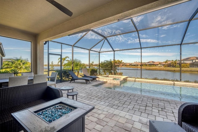 view of patio / terrace with a lanai, a water view, a pool with hot tub, and an outdoor fire pit