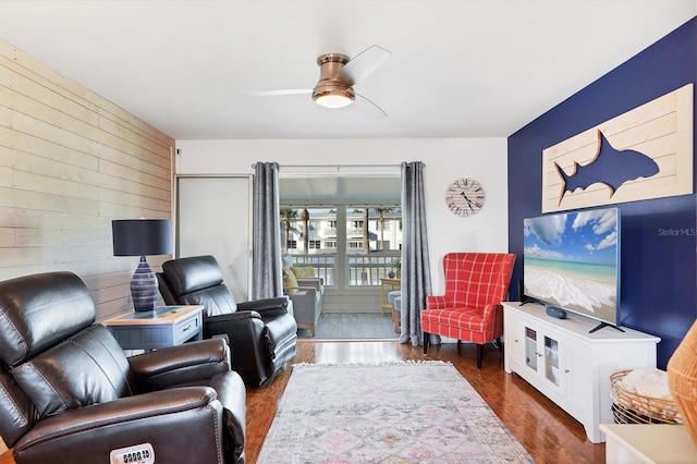 living room with wooden walls, ceiling fan, and dark hardwood / wood-style flooring