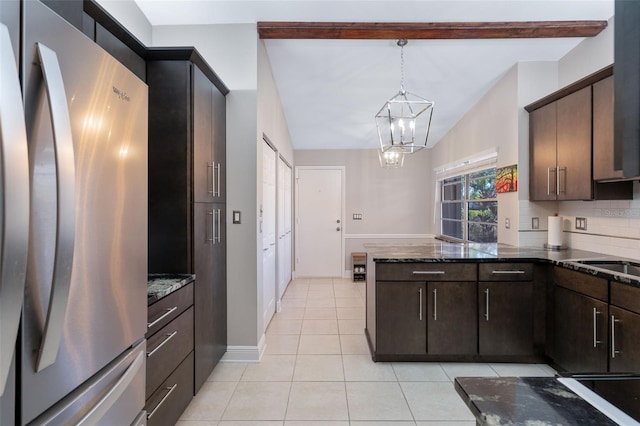 kitchen with stainless steel refrigerator, hanging light fixtures, dark brown cabinets, dark stone counters, and beamed ceiling