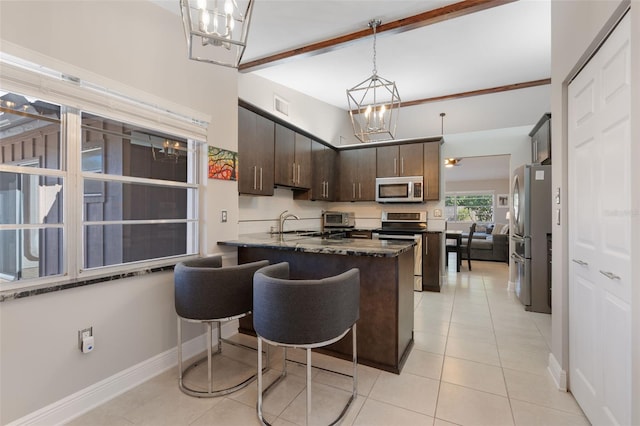 kitchen with sink, dark brown cabinets, appliances with stainless steel finishes, beamed ceiling, and dark stone counters