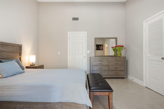 bedroom featuring a towering ceiling, a closet, and light tile patterned floors