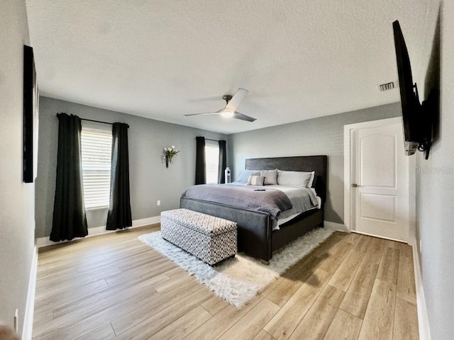 bedroom with a textured ceiling, ceiling fan, and light hardwood / wood-style flooring