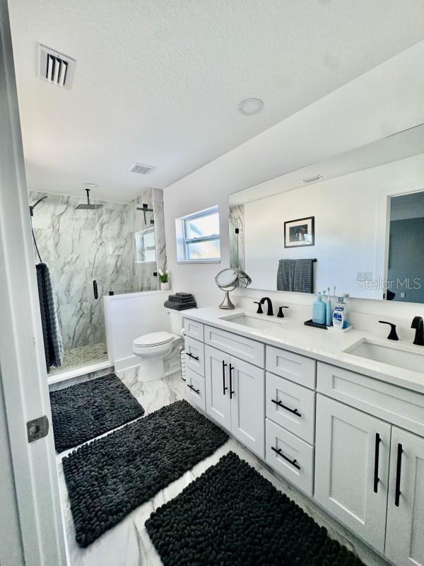 bathroom with vanity, a shower with shower door, a textured ceiling, and toilet