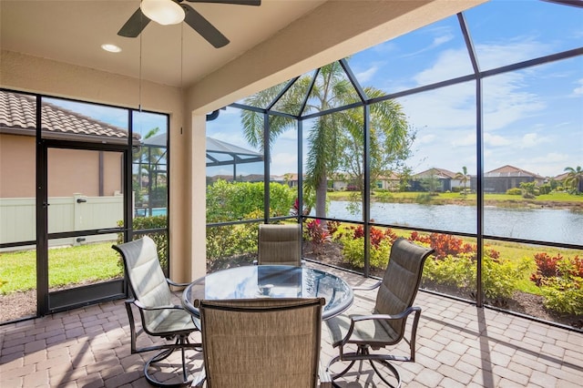 sunroom featuring ceiling fan and a water view