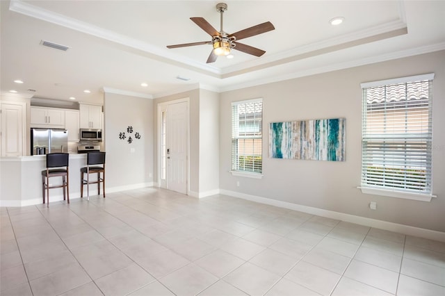 empty room with ornamental molding, a wealth of natural light, and a tray ceiling