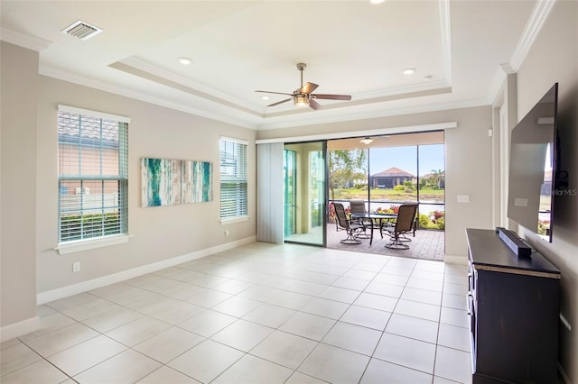 spare room with light tile patterned floors, a tray ceiling, ornamental molding, and a healthy amount of sunlight