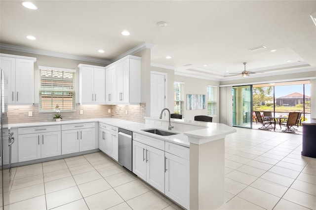 kitchen with sink, dishwasher, a tray ceiling, white cabinets, and kitchen peninsula