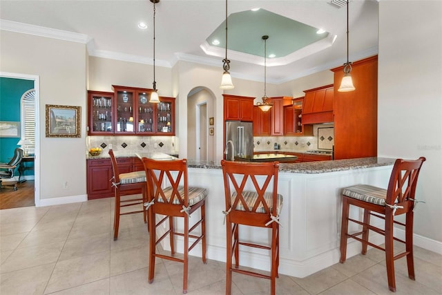 kitchen featuring pendant lighting, a breakfast bar area, high end fridge, a raised ceiling, and kitchen peninsula