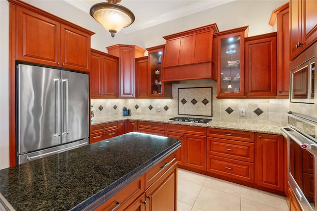 kitchen with light tile patterned flooring, tasteful backsplash, dark stone counters, stainless steel appliances, and crown molding