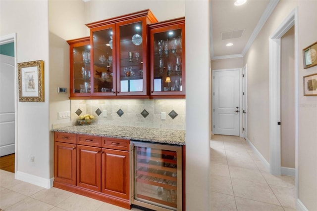 bar with wine cooler, crown molding, light stone counters, and light tile patterned floors