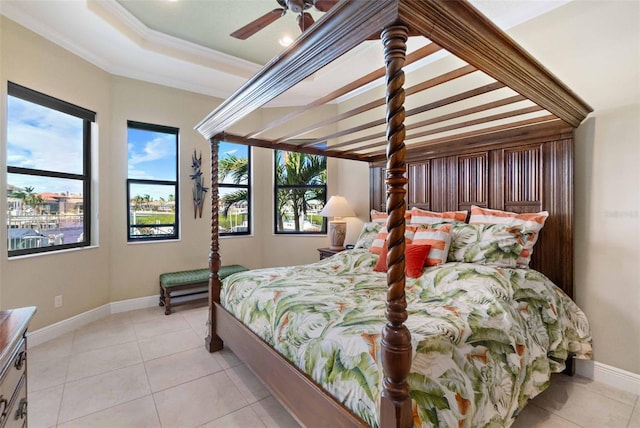 bedroom with light tile patterned flooring, ceiling fan, a tray ceiling, and crown molding