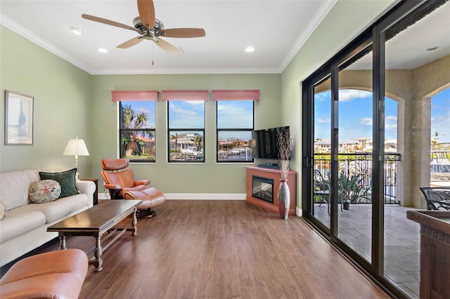 living room with ornamental molding, wood-type flooring, and ceiling fan