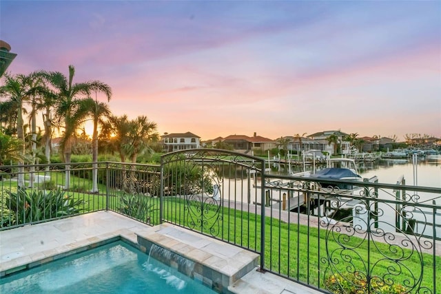 pool at dusk featuring a water view, a lawn, and a boat dock