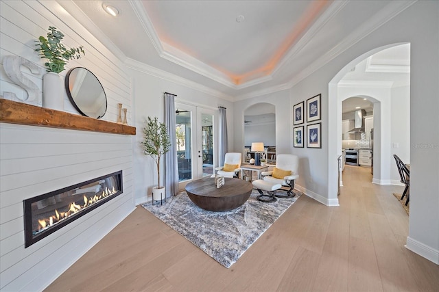 sitting room featuring a tray ceiling, ornamental molding, light hardwood / wood-style floors, and french doors