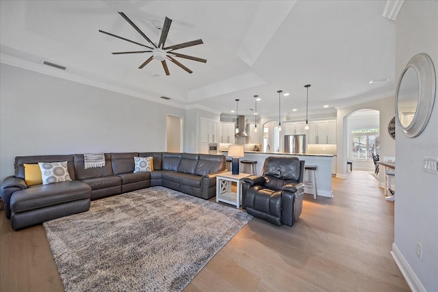 living room featuring crown molding, ceiling fan, and light hardwood / wood-style floors