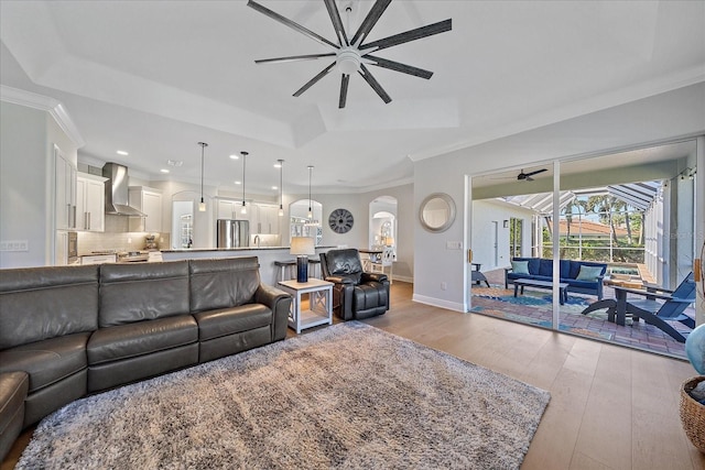 living room featuring a raised ceiling, ornamental molding, ceiling fan, and light hardwood / wood-style flooring