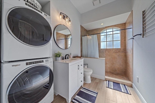 bathroom featuring walk in shower, stacked washer and dryer, vanity, and toilet