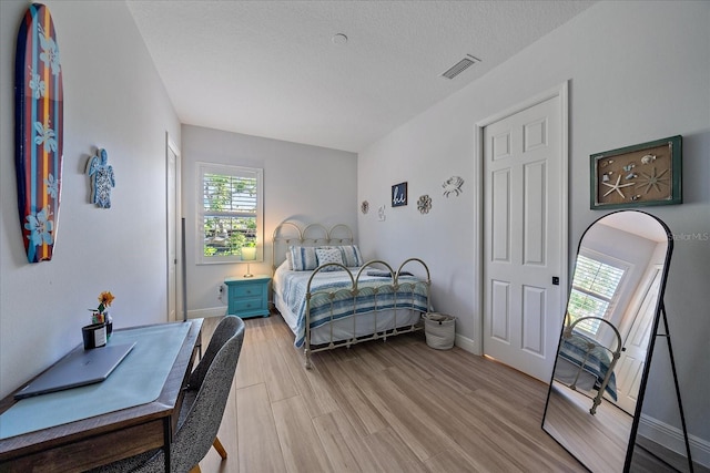 bedroom featuring light hardwood / wood-style floors and a textured ceiling