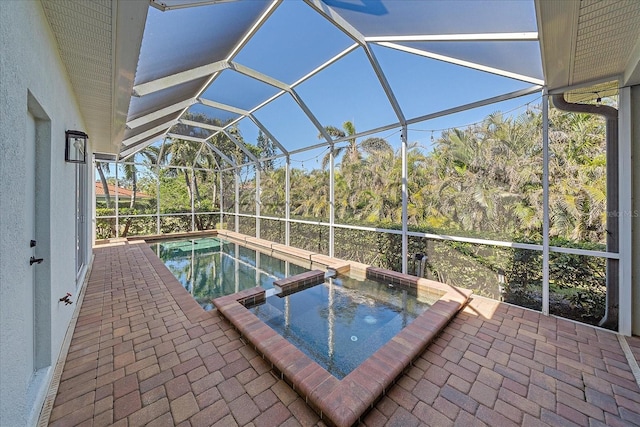 view of pool with a patio area, an in ground hot tub, and glass enclosure