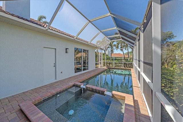 view of pool with an in ground hot tub, a patio, and glass enclosure