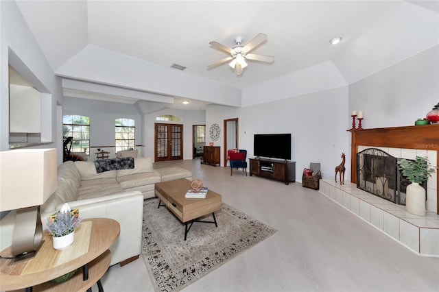 living room featuring a tiled fireplace, vaulted ceiling, and ceiling fan